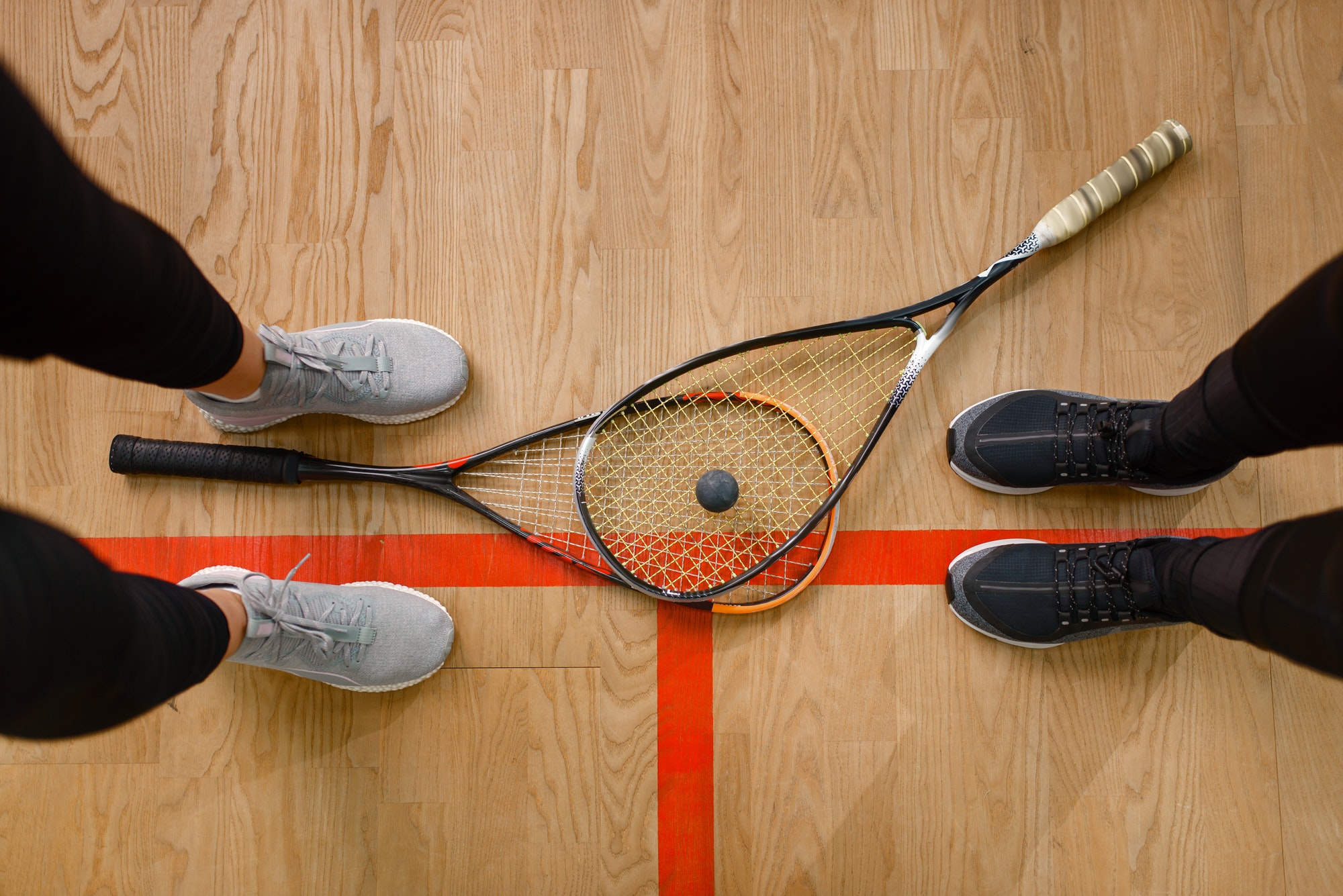 Female players legs and squash rackets, top view